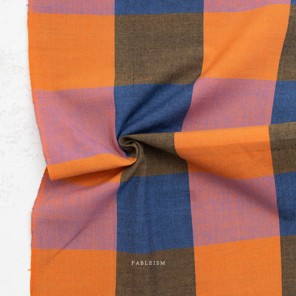 Checkered fabric with orange, blue, and brown squares on a white background, featuring the brand 'Fableism'.